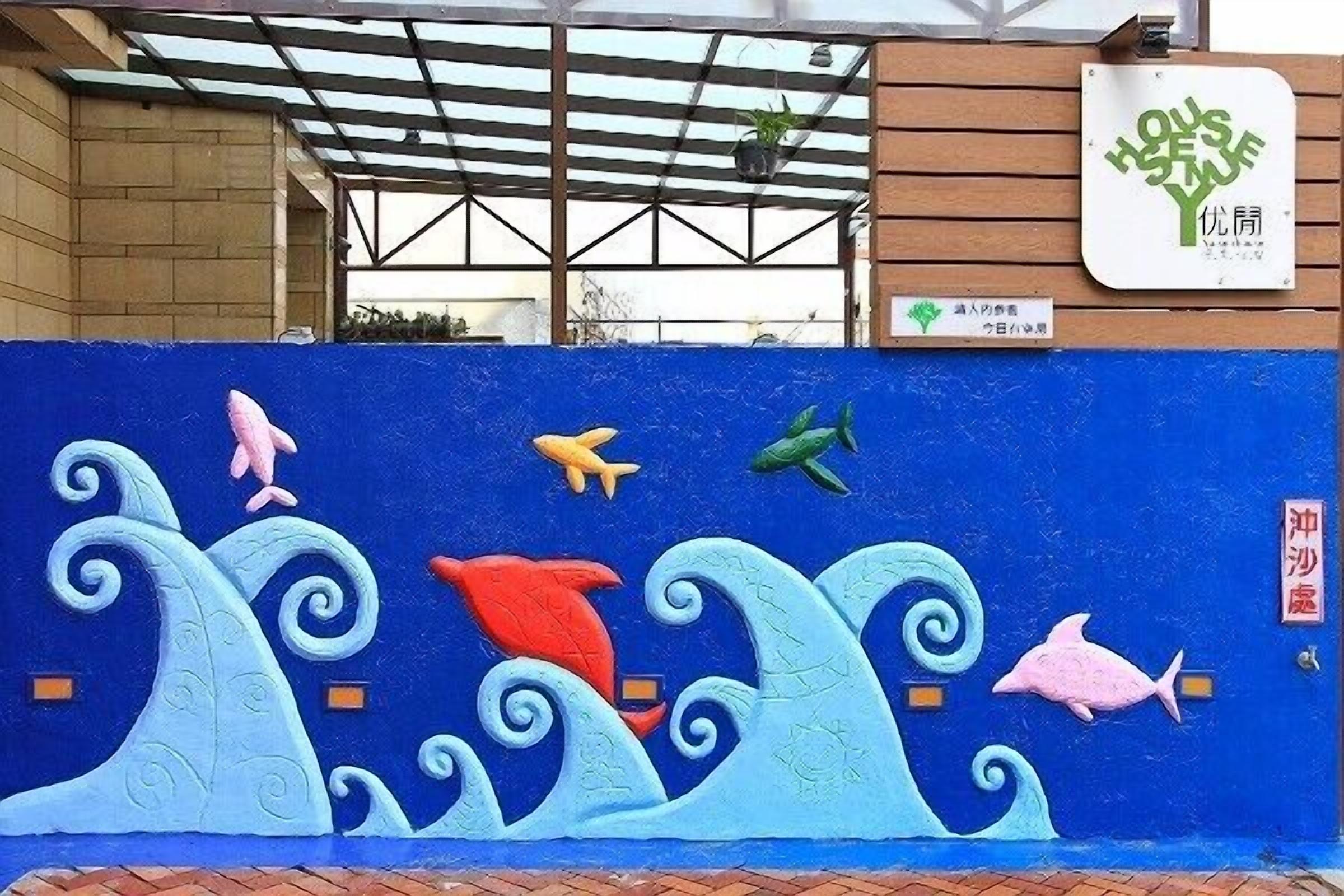 A blue wall with marine life murals, a wooden pergola, and a sign with a tree logo.