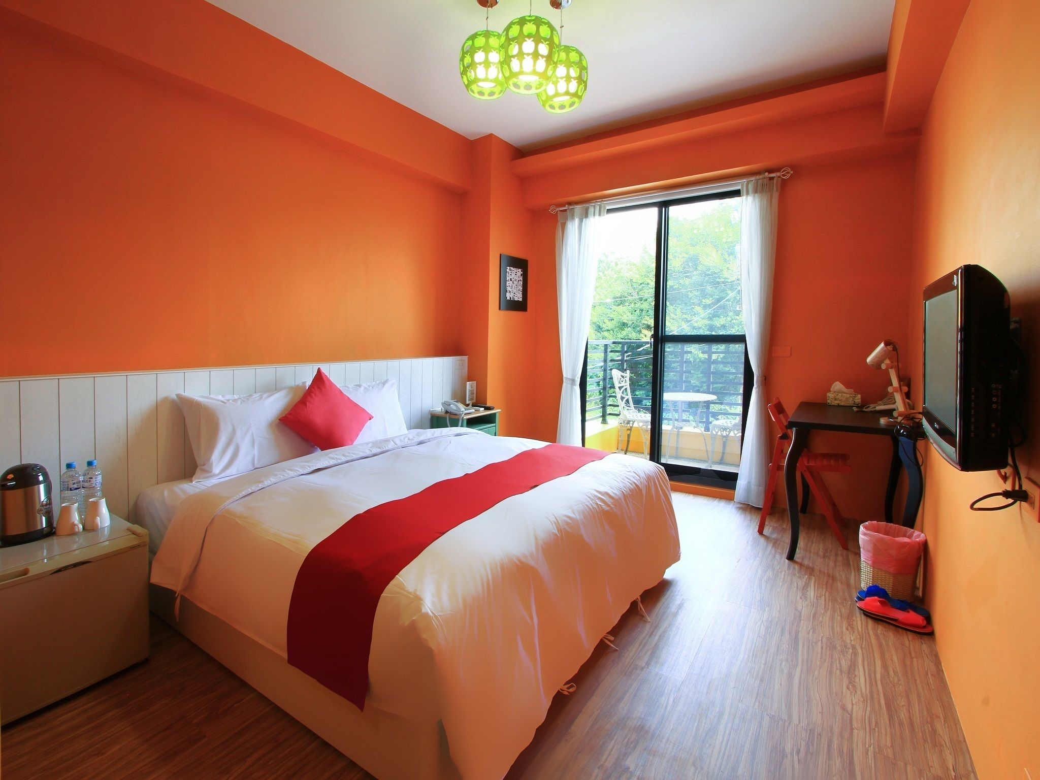 Quarto de hotel com uma cama grande, uma escrivaninha com cadeira, televisão e varanda com vista.