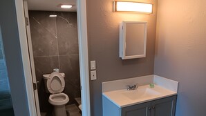 A bathroom with a toilet, sink, and mirror. - Budget Inn East (Kissimmee)