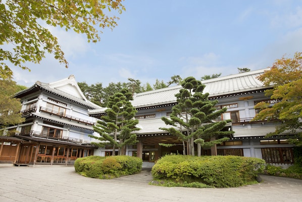 A traditional Japanese building with multiple floors, large windows, and a covered entrance. - Kusatsu Hotel (Kusatsu)