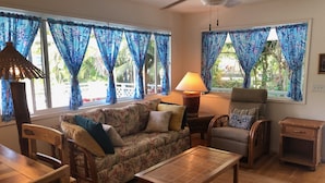 A living room with a sofa, chairs, a table, and a lamp. - Ala Kai Bed & Breakfast (Keaau)