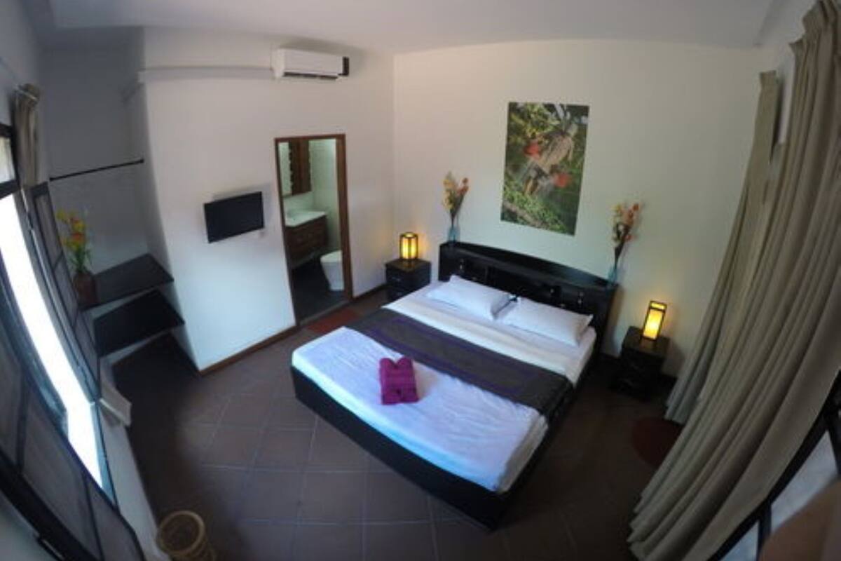 A hotel room with a large bed, a flat-screen TV, a bedside table with a lamp, and a window with curtains.