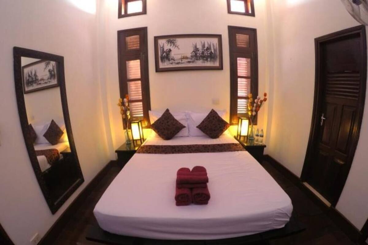 A hotel room with a bed, two bedside tables, a mirror, and a door.