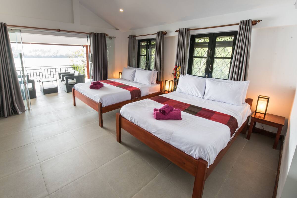 A hotel room with two beds, a balcony, and a view of the water.