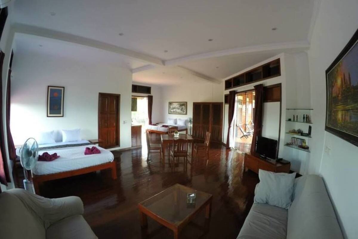 A spacious living room with a large sofa, a coffee table, and a dining area with wooden furniture.