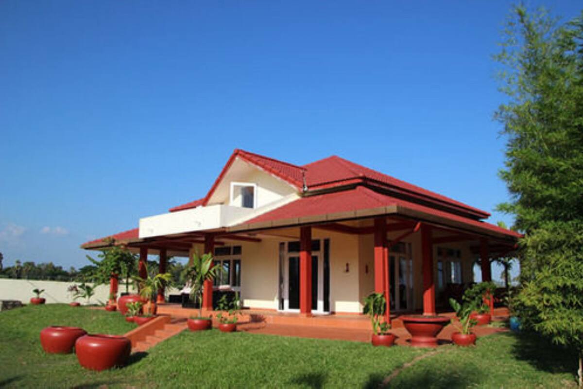 A modern house with a red roof and white walls, surrounded by a well-maintained lawn and large potted plants.