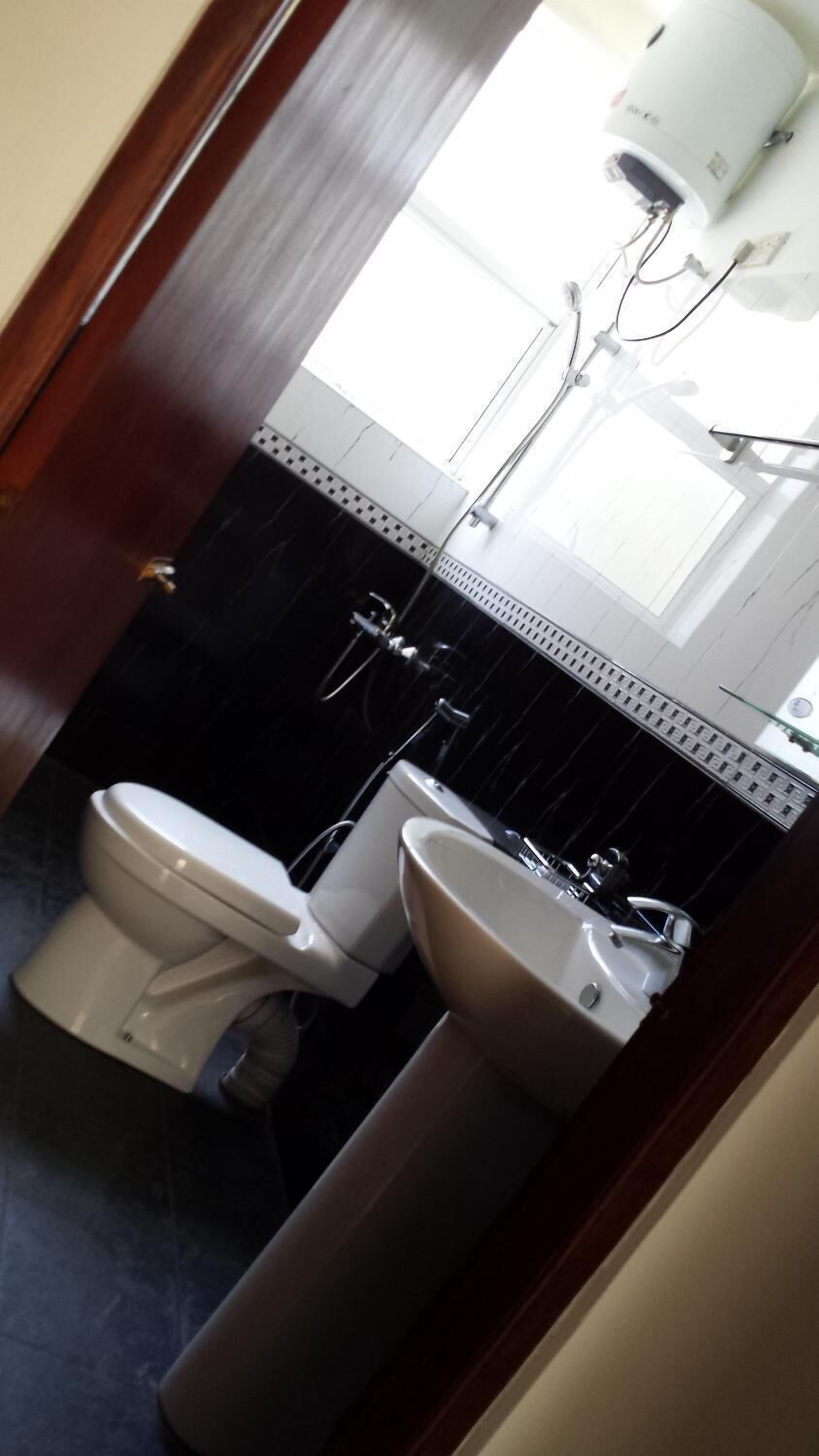 Un baño con inodoro, lavamanos y espejo.