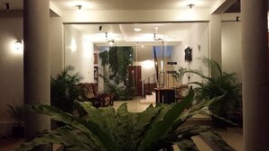 A spacious lobby with a central staircase, multiple seating areas, and abundant indoor plants. - Nooit Gedacht Holiday Resort (Unawatuna)