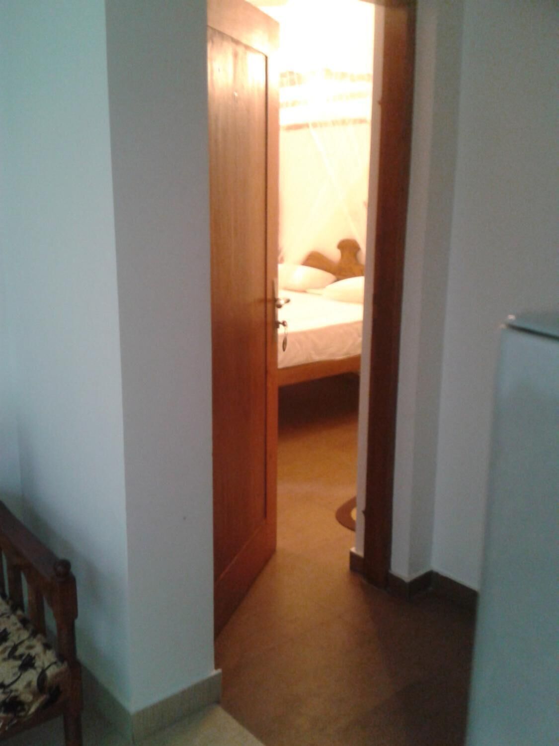 Un pasillo estrecho que conduce a un dormitorio con una cama y una mesita de noche.