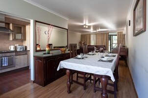 A dining area with a table set for four, a kitchen with modern appliances, and a large mirror above the counter.