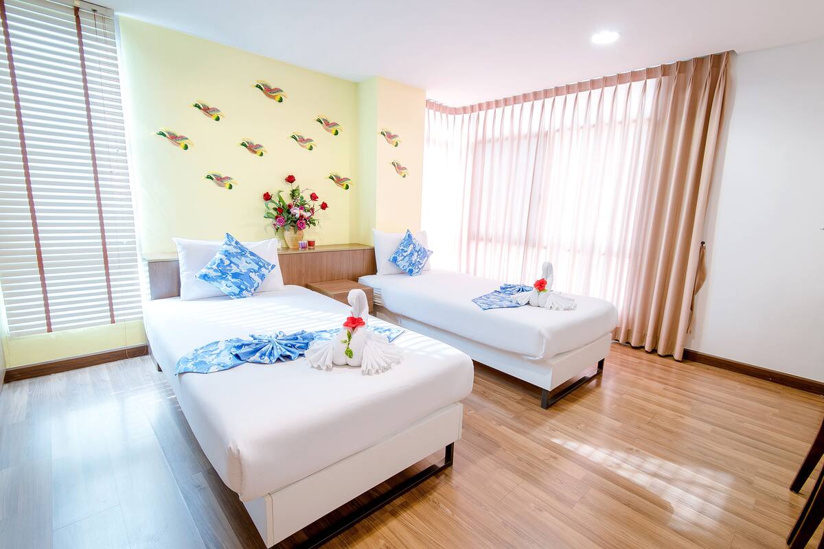 A hotel room with two beds, a wooden floor, and a wall decorated with bird decals.