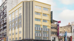A multi-story hotel with a yellow facade and vertical grey stripes.