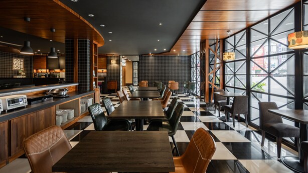 A modern restaurant with a checkered floor, wooden ceiling, and large windows.