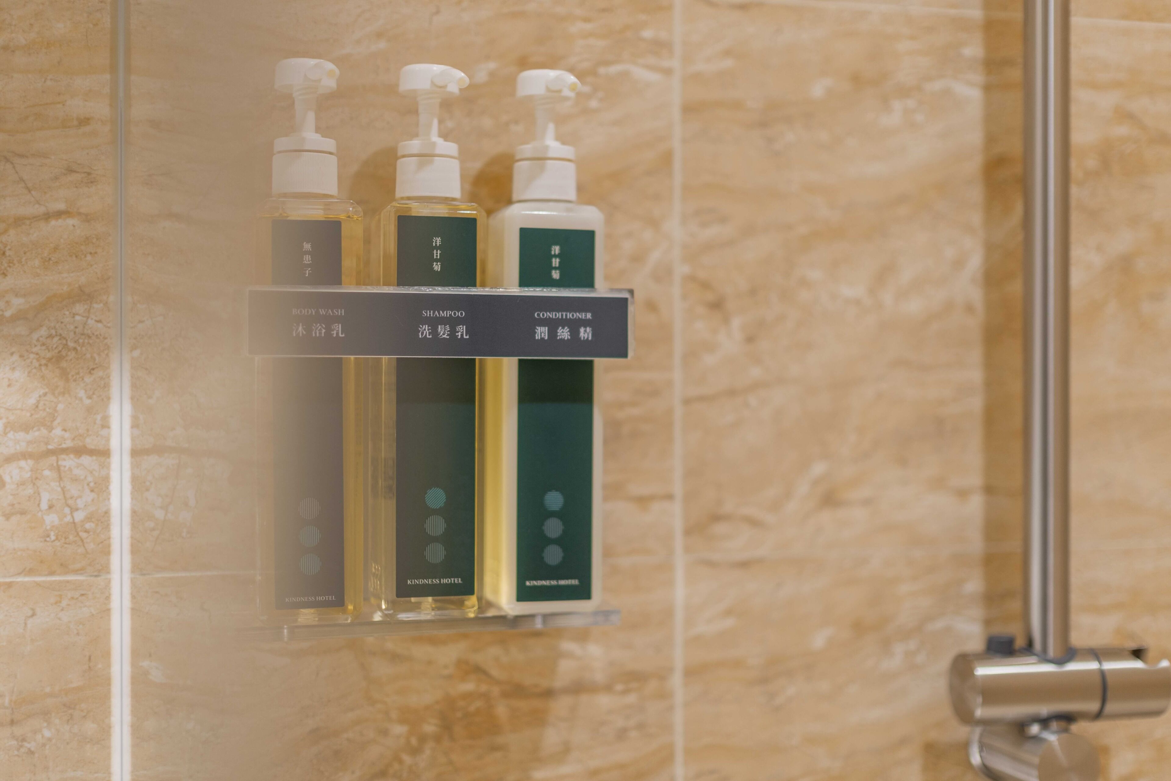 A bathroom with a glass shelf holding three bottles of toiletries labeled 'BODY WASH,' 'SHAMPOO,' and 'CONDITIONER.'