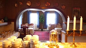 A dining area with a long table set for a meal, a chandelier, and a candelabra with candles.