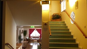 A staircase with green steps leading to a landing, a clock on the wall, and a plant on the landing.