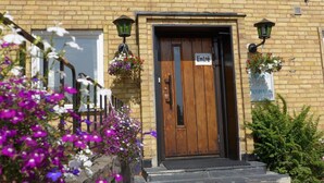 A brick building with a wooden door labeled "Entré".