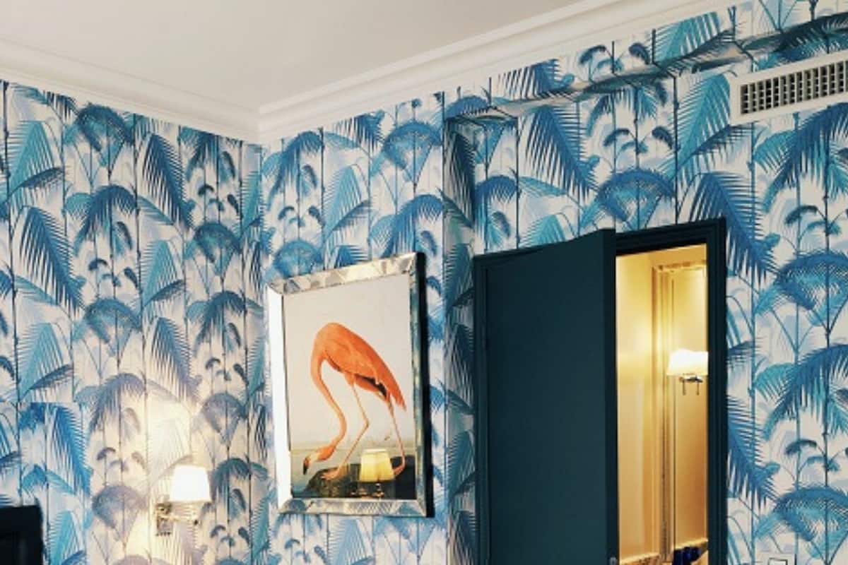 A hotel room with a bed, a nightstand, a framed picture of a flamingo, and a door leading to a bathroom.