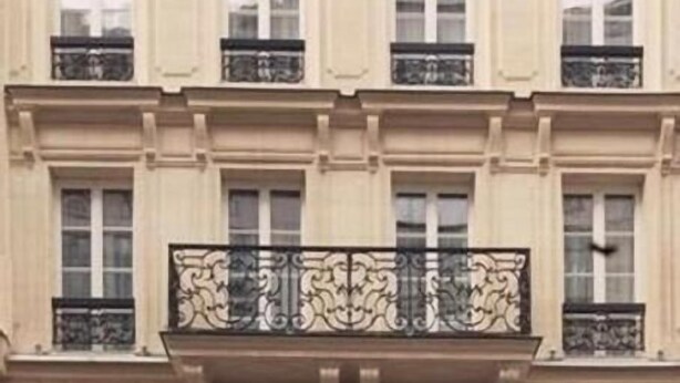Un edificio de varios pisos con estilo arquitectónico clásico, con ventanas regularmente distribuidas y barandillas de hierro decorativas en los balcones.