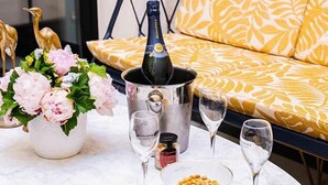 Una mesa con una botella de champán, un arreglo floral y un cuenco de frutos secos.