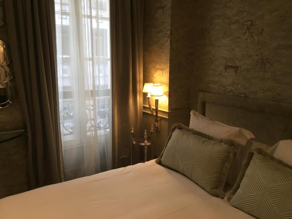 Ein Hotelzimmer mit einem Bett, Vorhängen, einer Lampe und einer Wand mit Tierreliefs.