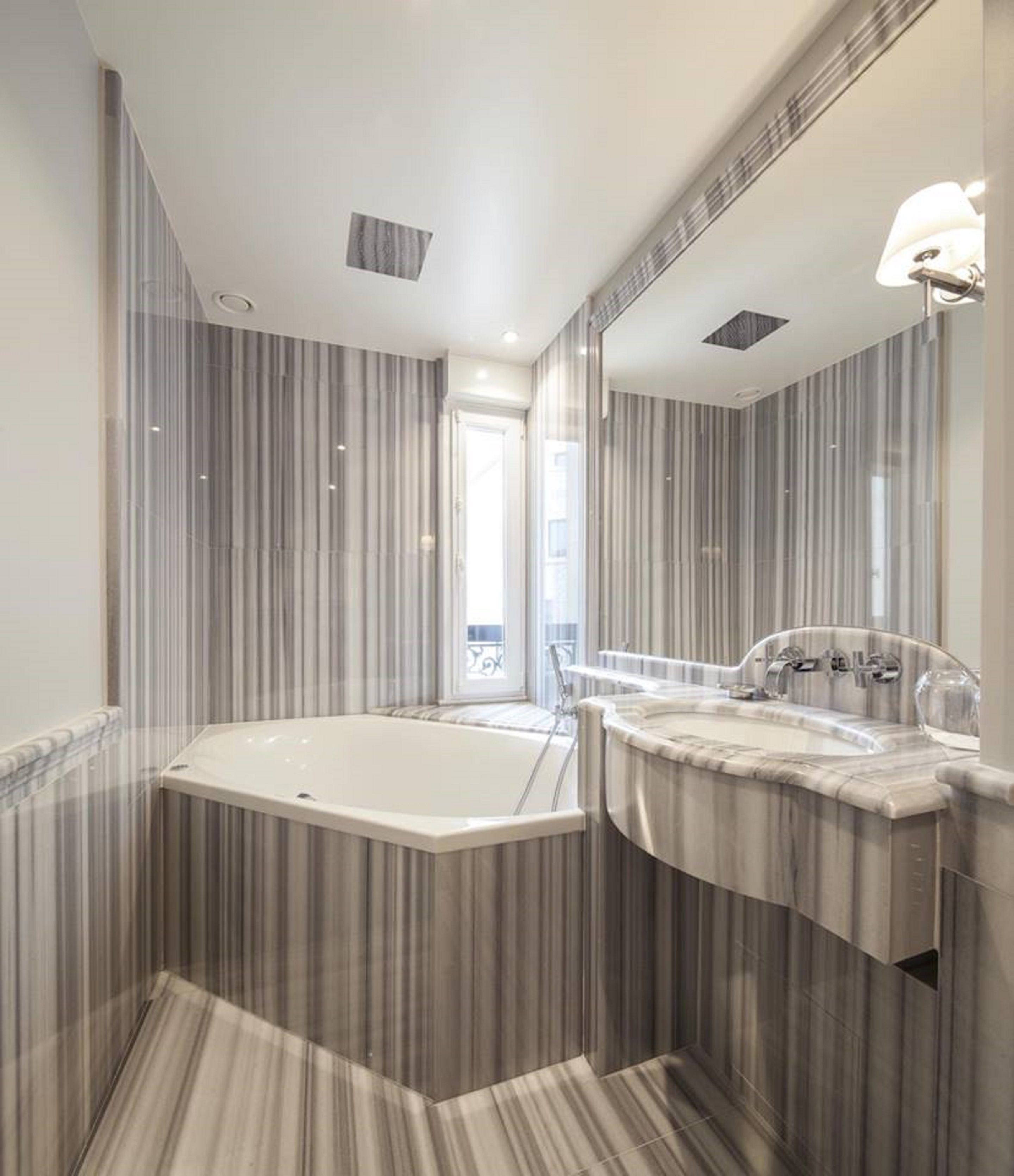 Une salle de bain moderne avec une baignoire sur pieds, un grand miroir et des panneaux muraux à rayures.