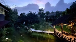 A serene outdoor area with a wooden deck, lush greenery, and a clear sky. - Montania Lifestyle Hotel (Phanom)