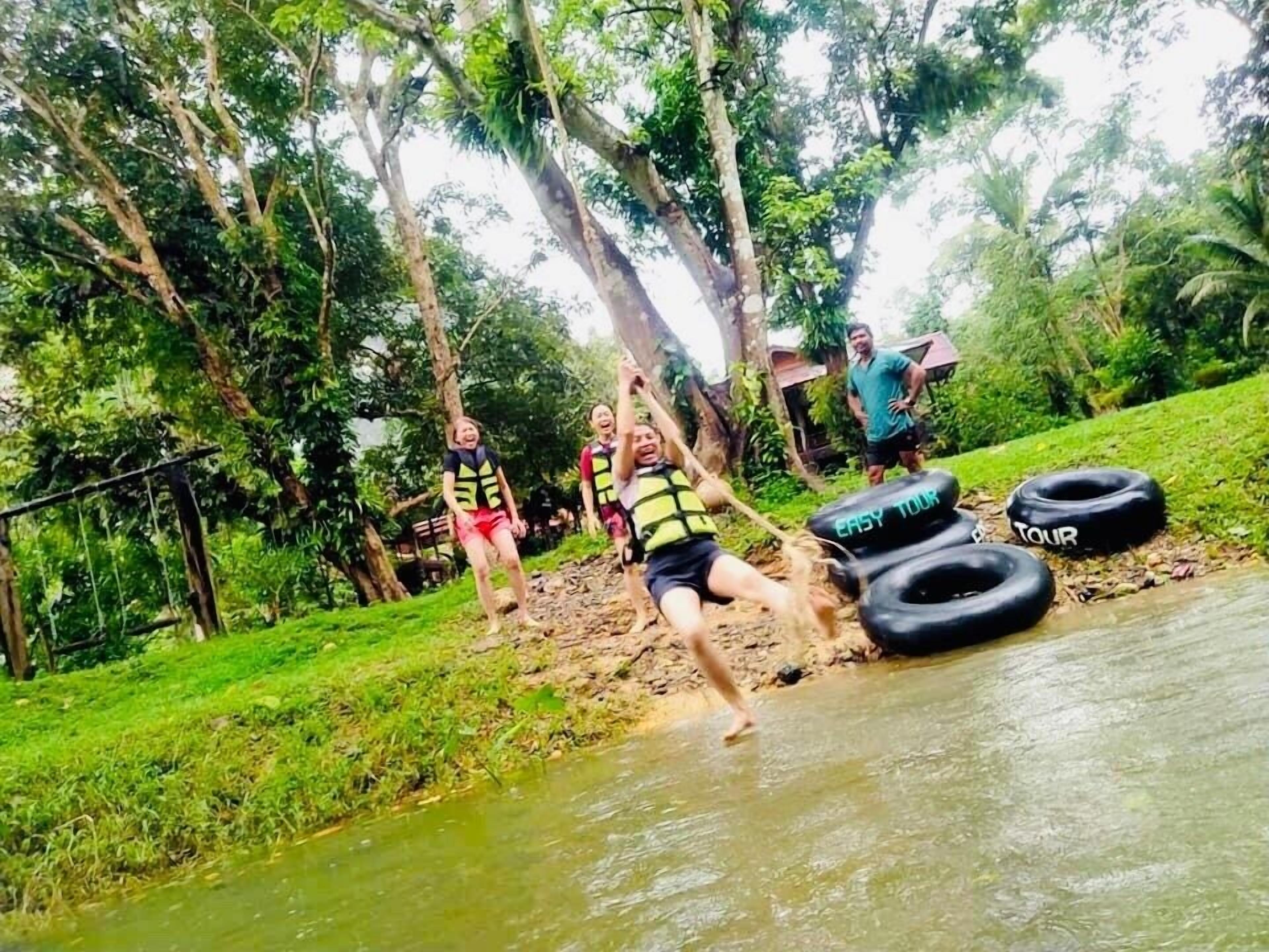 A group of people in a natural setting with a water body and trees.