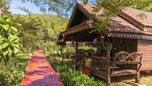 A traditional wooden building with a tiled roof, a red pathway leading to it, and a bench outside. - Montania Lifestyle Hotel (Phanom)