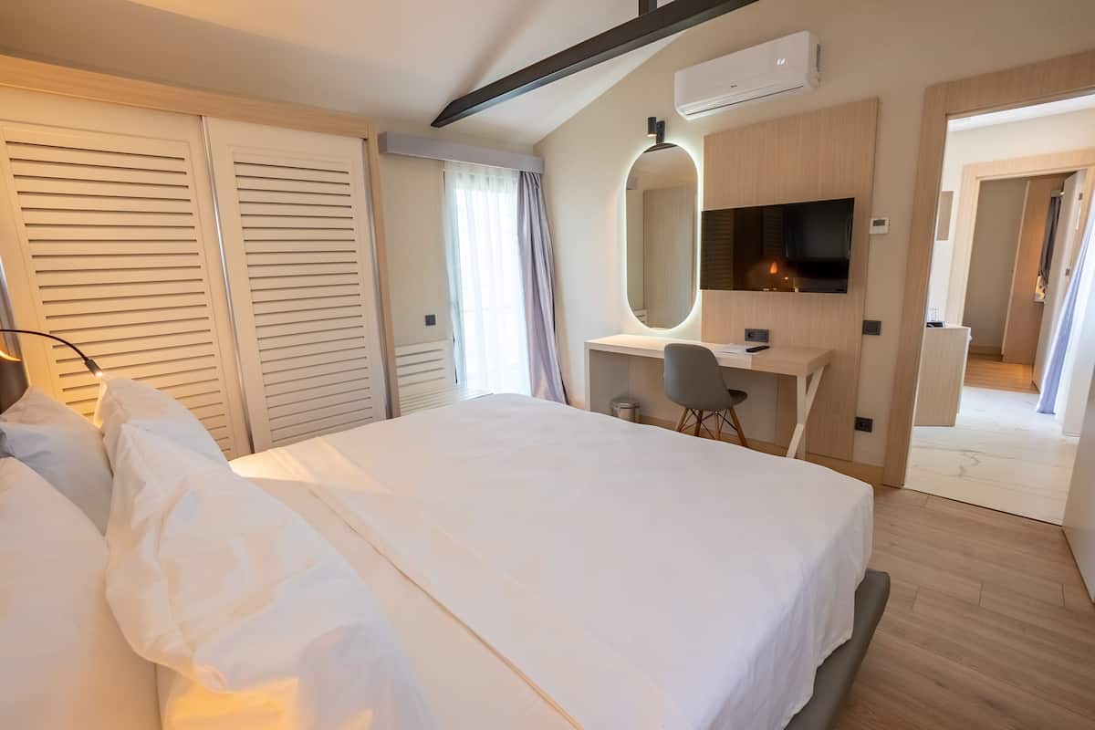 Une chambre d’hôtel comprenant un lit, un bureau avec une chaise, une télévision et un grand miroir.