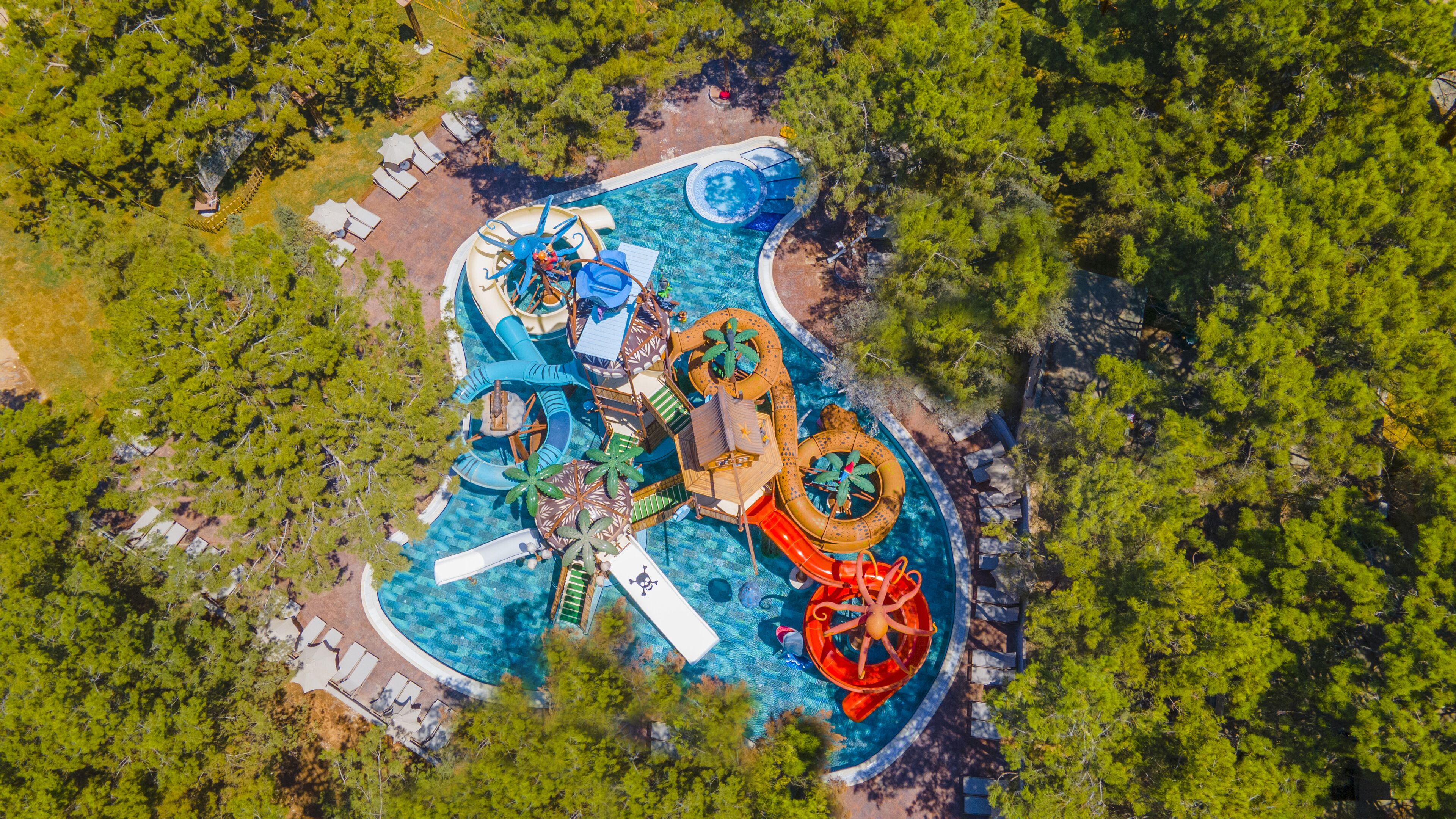 Luchtbeeld van een waterpark met glijbanen en zwembaden, omgeven door bomen.