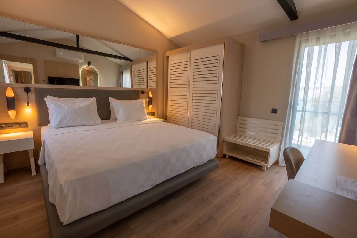 Une chambre moderne avec un grand lit, des tables de chevet, un miroir, une armoire et un bureau.