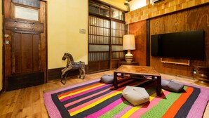A traditional Japanese room with tatami flooring, a shoji screen door, a television, and a horse sculpture.