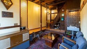 A traditional Japanese-style interior with a reception desk, seating area, and a staircase.