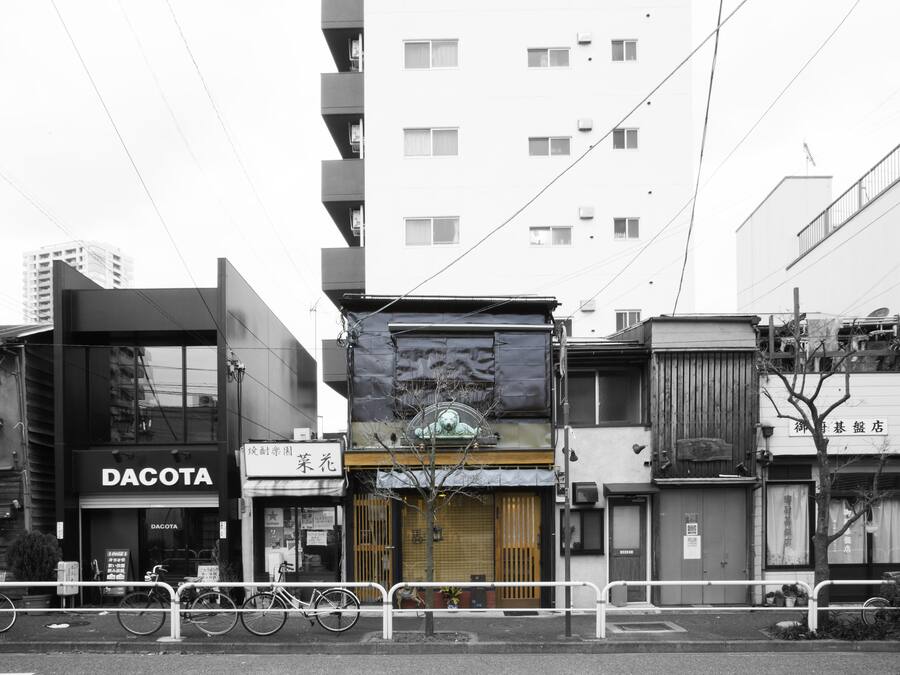 A street view with a building labeled "DACOTA" and another with a sign in a foreign language.