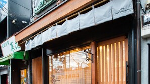 A traditional Japanese building with a wooden facade, large sliding doors, and a small balcony.