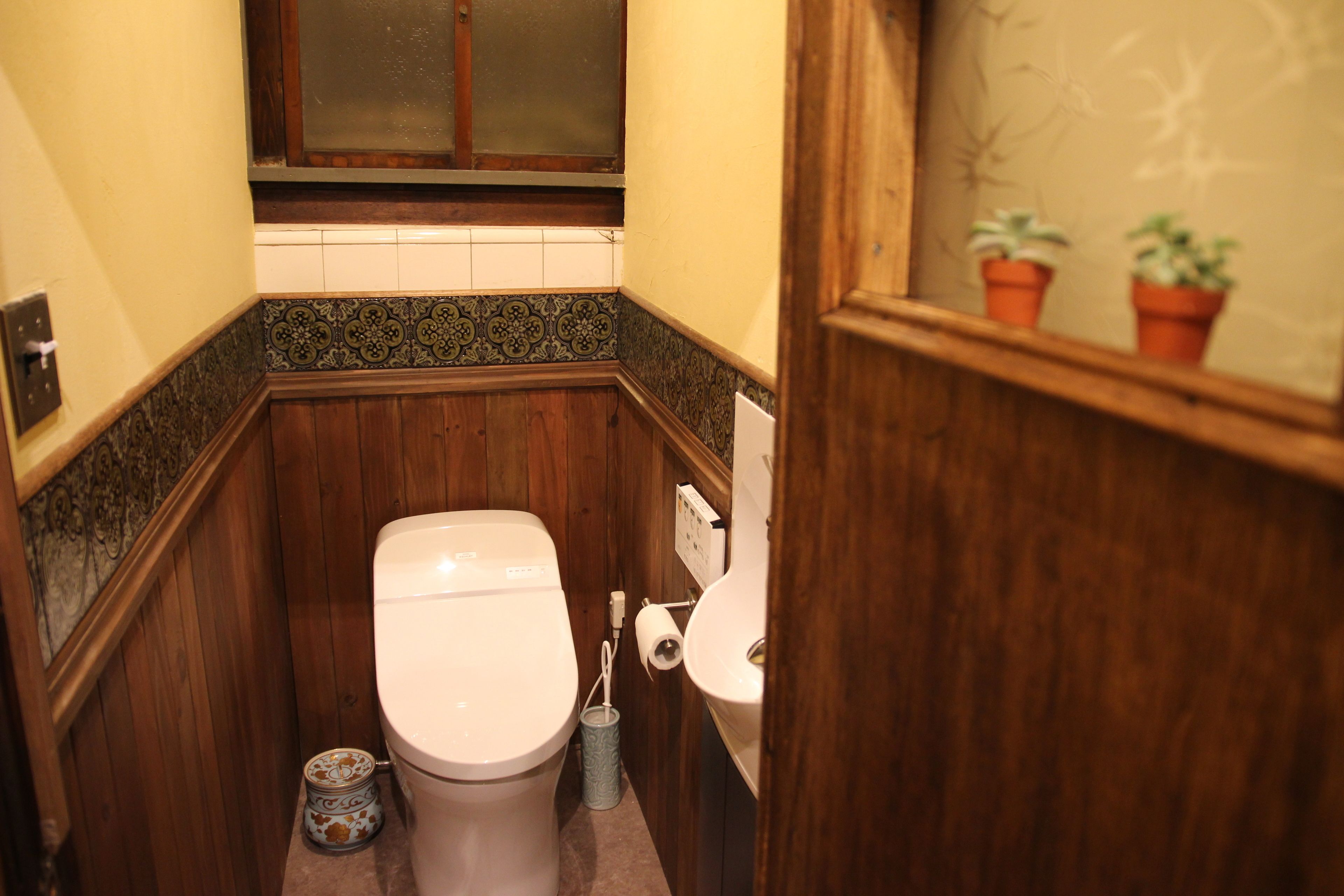 A small, narrow bathroom with wooden walls and a tiled backsplash.