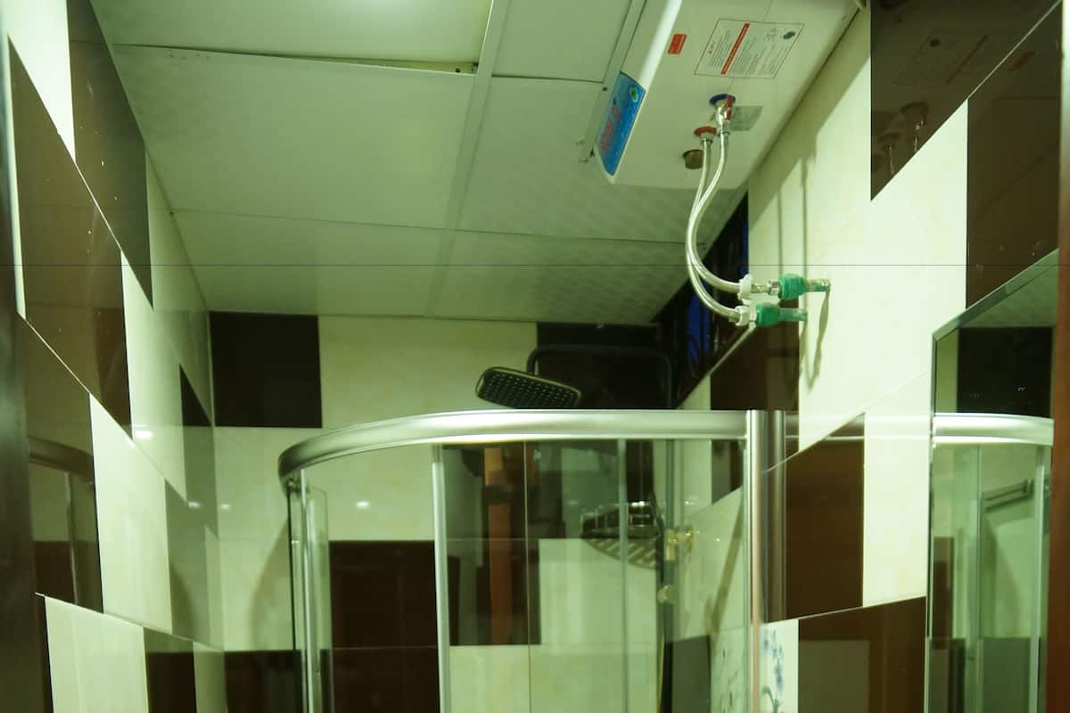 Een moderne badkamer met een douchecabine van glas, een wit wastafeltje en een toilet.