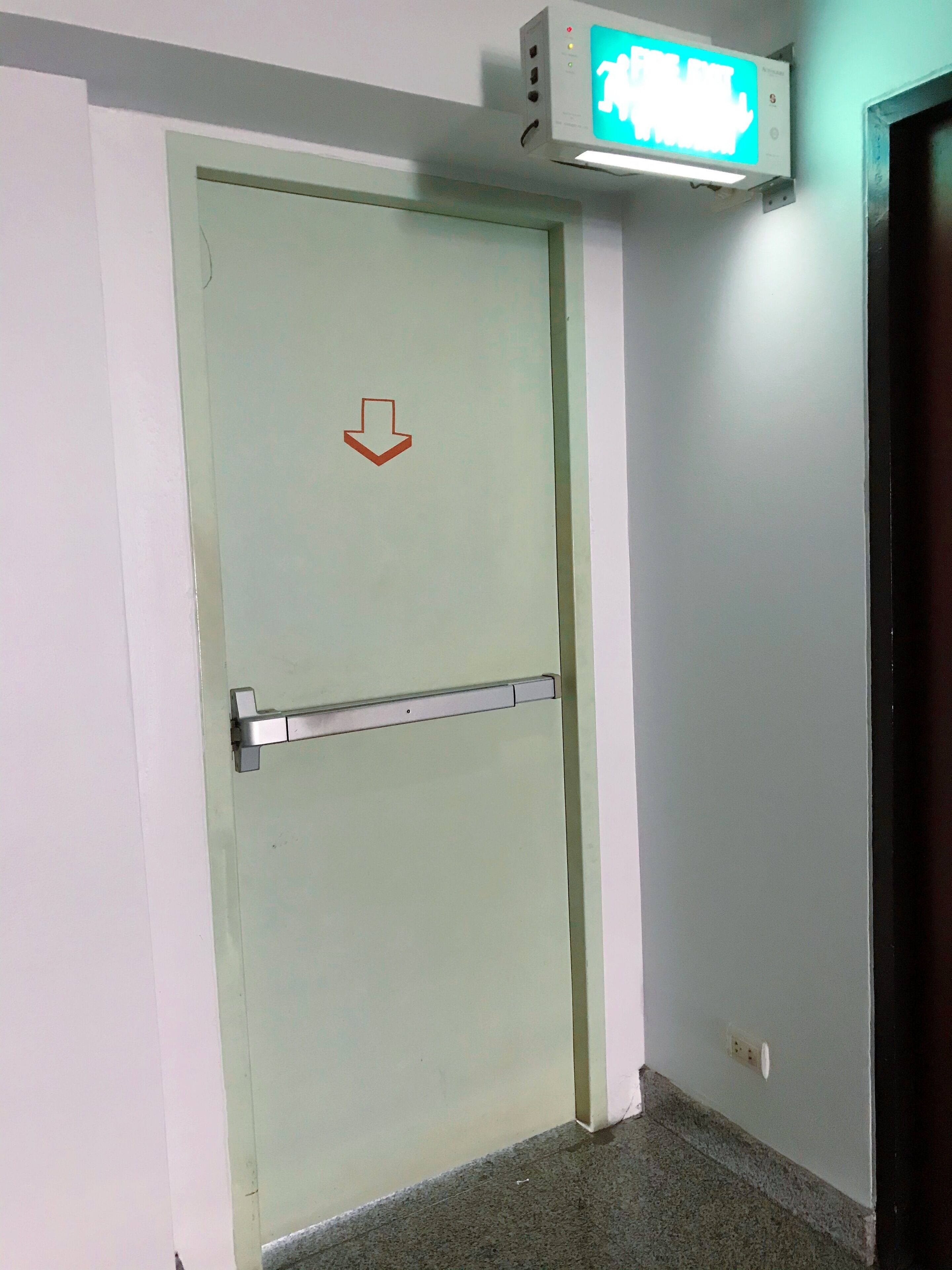 A door with a downward arrow sign, a metal handle, and a light switch above it.