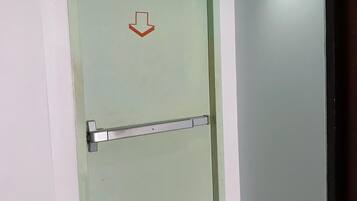 A door with a downward arrow sign, a metal handle, and a light switch above it.