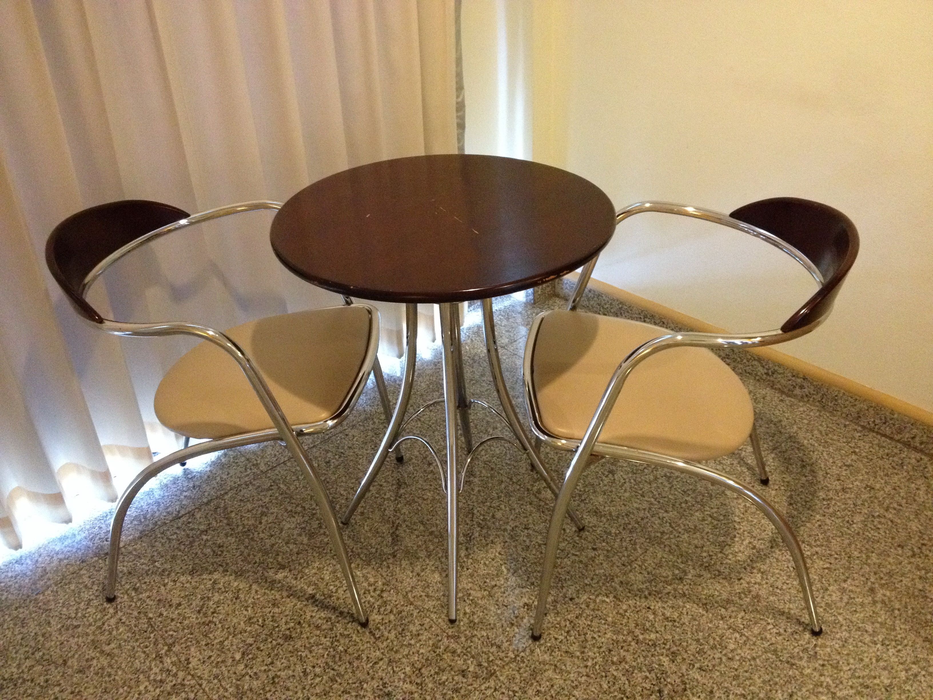 A round table with four chairs, each with a cushioned seat and backrest. The table and chairs are made of metal.