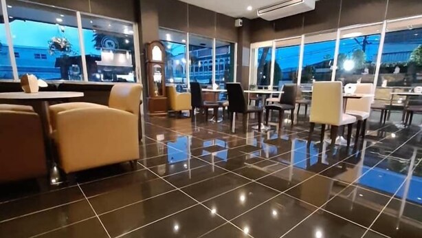 A modern hotel lobby with a polished floor, seating areas, and large windows offering views of the cityscape. - Maneerote Hotel Surin (Surin)