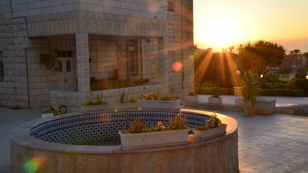 A courtyard with a fountain, potted plants, and a building with stone walls. - Auberg-Inn Guesthouse (Jericho)