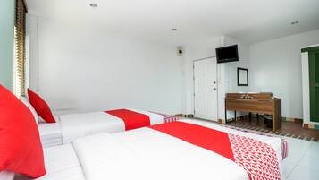 Ein Hotelzimmer mit zwei Betten, einem Schreibtisch, einem Fernseher und einer Tür mit grünem Rollo.