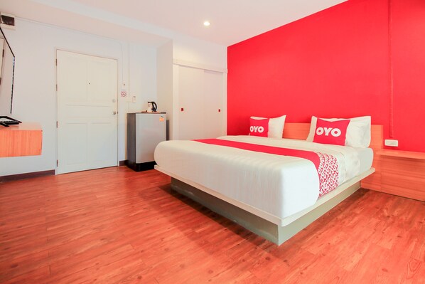 Une chambre d’hôtel moderne avec un grand lit, un mur d’accent rouge et un plancher en bois.