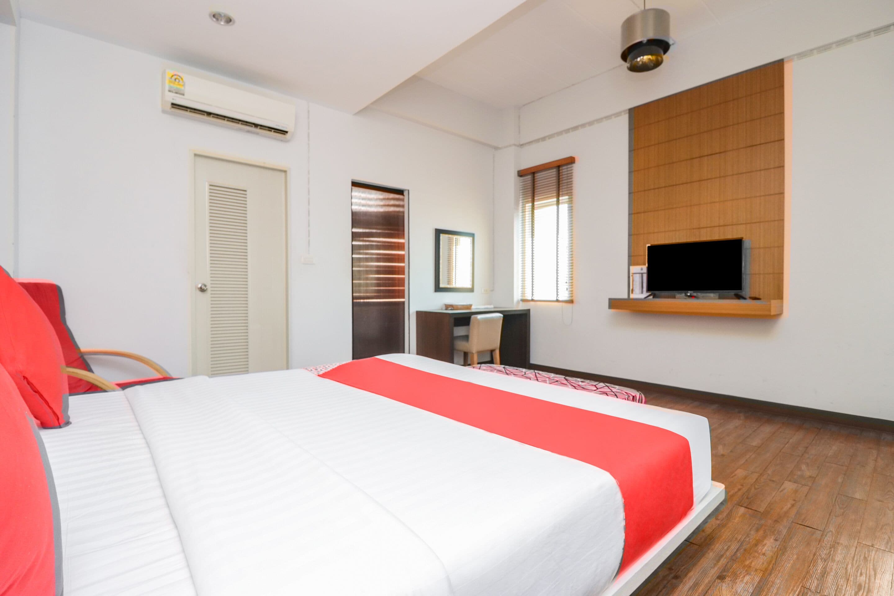 Ein Hotelzimmer mit Bett, Schreibtisch, Fernseher und einem Fenster mit Jalousien.