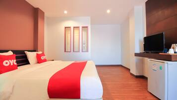 A hotel room with a bed, a TV, and a mini-fridge.