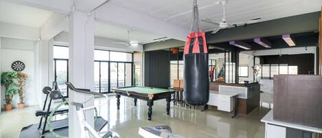 Amplo espaço interno com mesa de bilhar, equipamentos de ginástica e saco de pancadas.