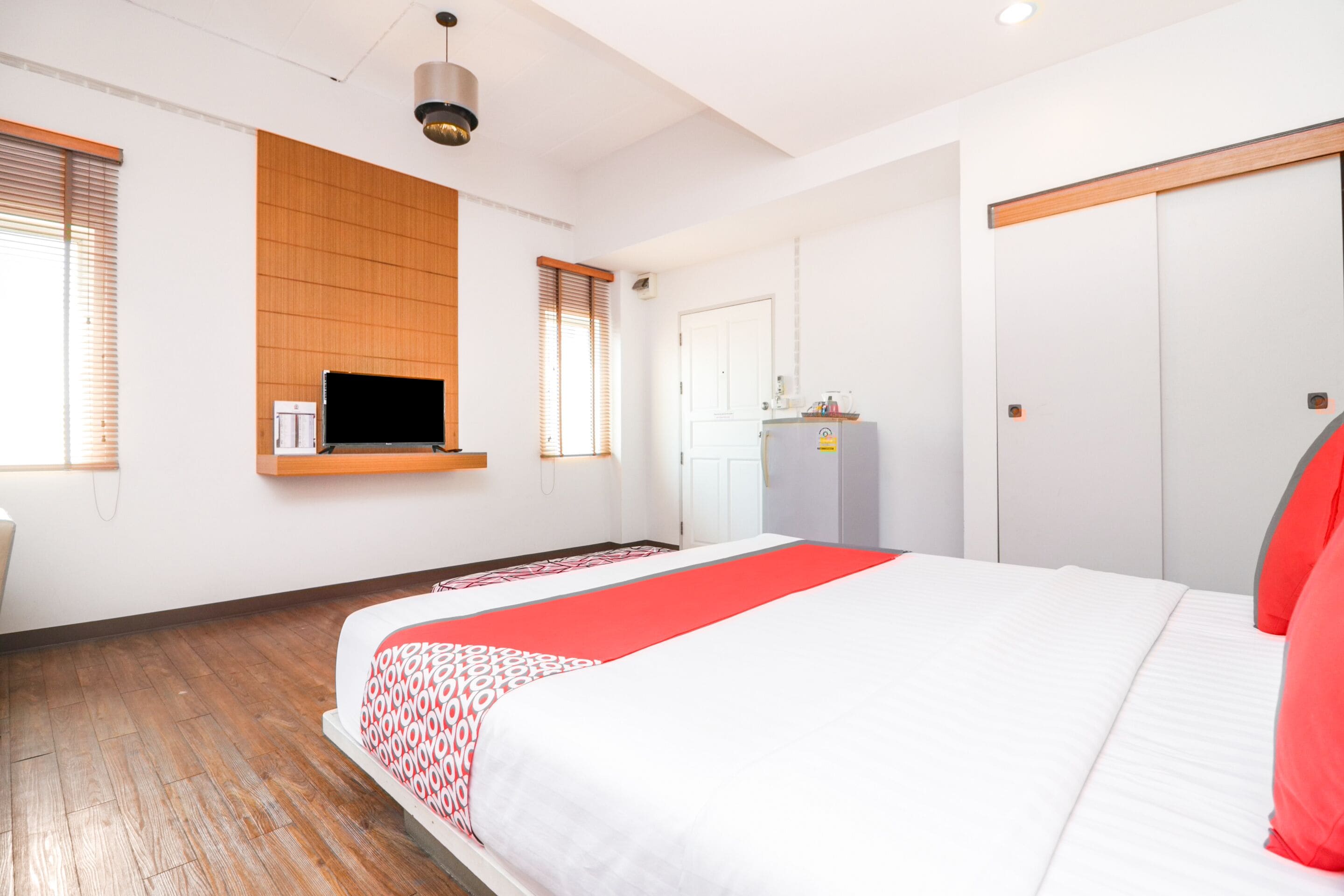 A modern hotel room with a large bed, wooden panel wall, a flat-screen TV, and a wardrobe.