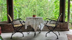 A table with a lace tablecloth and two chairs, set against a backdrop of greenery. - Assos Nar Konak (Ayvacik)